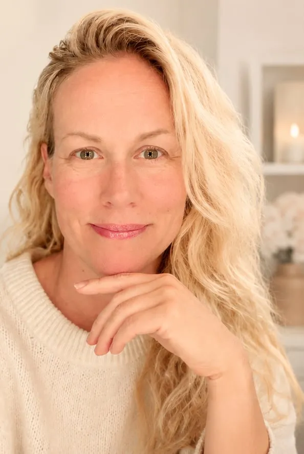 Ann-Sofie i en stickad tröja, hakan vilande mot handen.